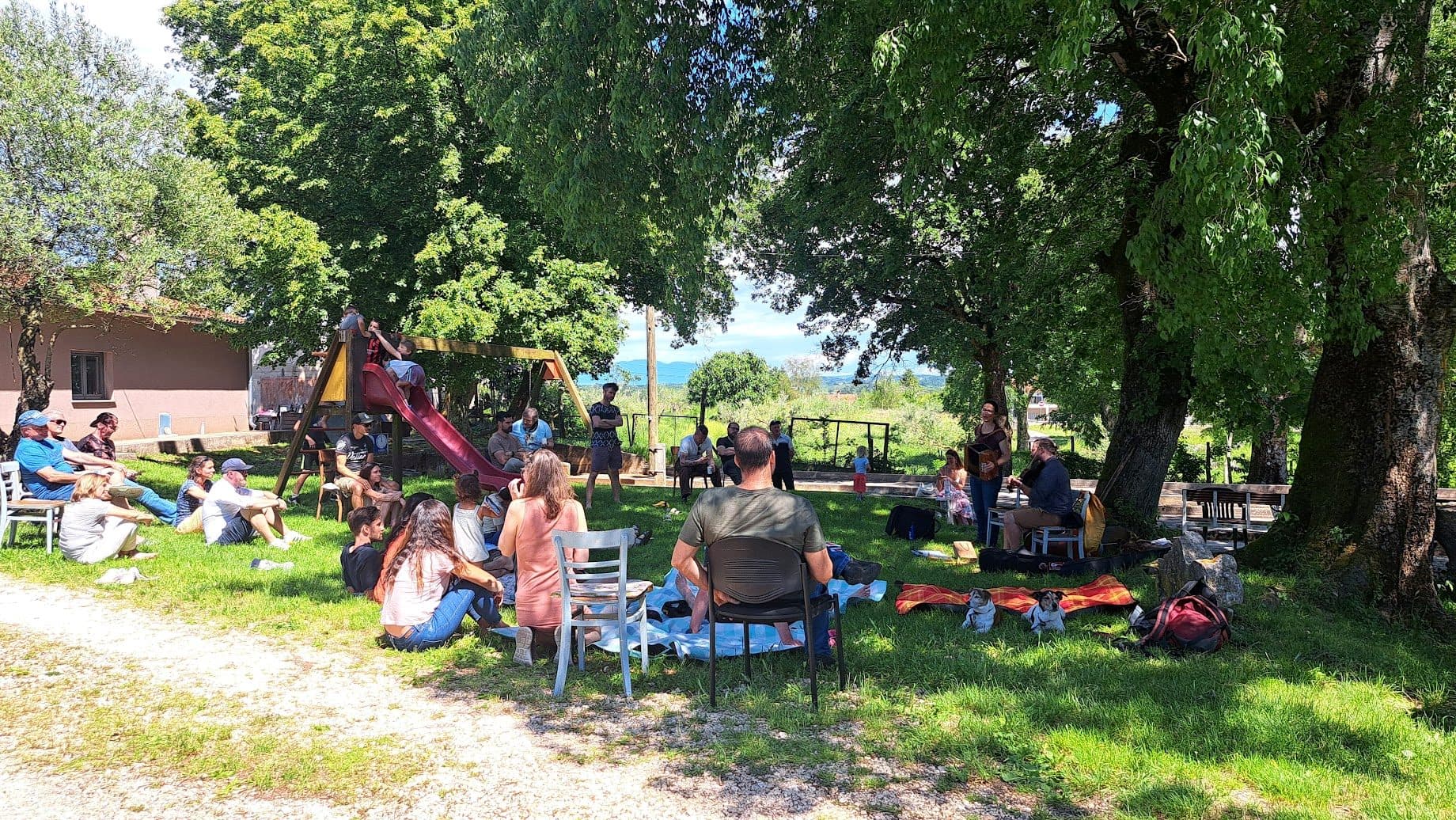 Families gathered in the shade of old trees at the completed location